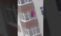 Bebaimė moteriškė valo langus penktame aukšte